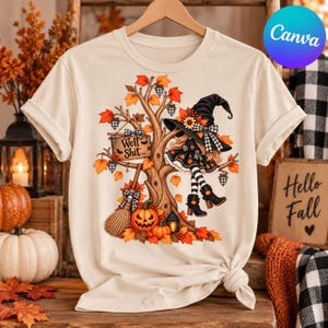 May include: A cream-colored t-shirt featuring a graphic of a witch sitting in a tree surrounded by autumn leaves, a pumpkin, a broom, and a sign that reads Well Shit. The design includes orange, brown, and black colors with a plaid pattern.