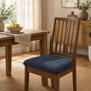 Puede incluir: Una silla de comedor de madera con una funda de asiento de color azul oscuro con un patrón de cuadrícula texturizado. La silla tiene un respaldo alto con listones verticales y cuatro patas resistentes. El cojín está cubierto de tela acanalada.