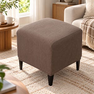 May include: A square ottoman upholstered in a brown corduroy fabric with vertical ribbed texture. The piece features four tapered black legs that provide a stable base, creating a functional furniture item for seating or resting feet.