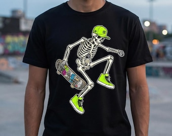 May include: A black t-shirt featuring a graphic of a skeleton wearing a bright lime green baseball cap and matching high-top sneakers. The skeleton is depicted in a dynamic pose, holding a skateboard decorated with colorful stickers.