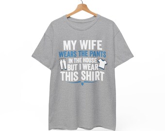 May include: A heather gray short-sleeve t-shirt featuring the white and blue text "MY WIFE WEARS THE PANTS IN THE HOUSE BUT I WEAR THIS SHIRT" along with small graphic icons of a pair of pants and a t-shirt printed on the front center.