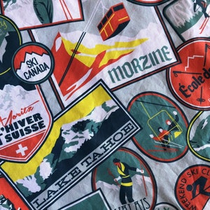 May include: A colorful fabric with a repeating pattern of vintage ski resort patches. The patches feature mountain scenes, ski lifts, and text in various languages, including "St. Moritz L'Hiver en Suisse", "Ski Canada", "Morzine", and "École de Ski en Suisse".