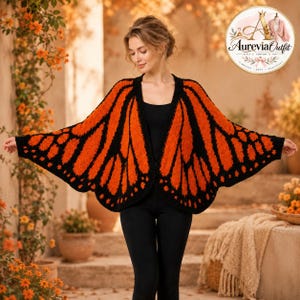 May include: A knitted cardigan featuring a vibrant orange and black monarch butterfly wing pattern. The garment has an open front, wide sleeves, and a textured finish. It is worn over a plain black top and black leggings, creating a cohesive look.