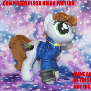 May include: A gray and blue plush pony with brown hair. The pony is wearing a blue jacket with a silver and black armband. The pony is standing on a purple and white background with white hearts.