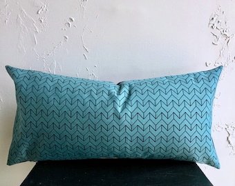 May include: A teal blue rectangular pillow with a black chevron pattern.