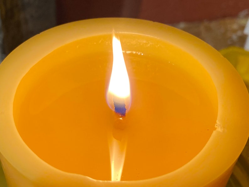May include: A yellow candle with a single flame burning in the centre.