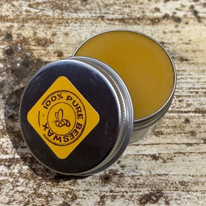 May include: A small tin container of pure beeswax, with a yellow lid that says "100% Pure Beeswax".
