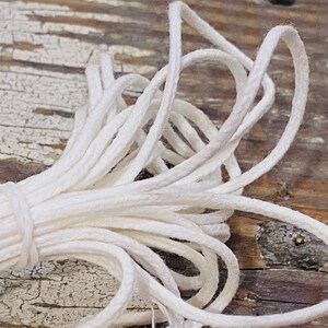 May include: A close-up of a white cotton cord, twisted and bundled together. The cord is soft and pliable, perfect for crafting or jewelry making.
