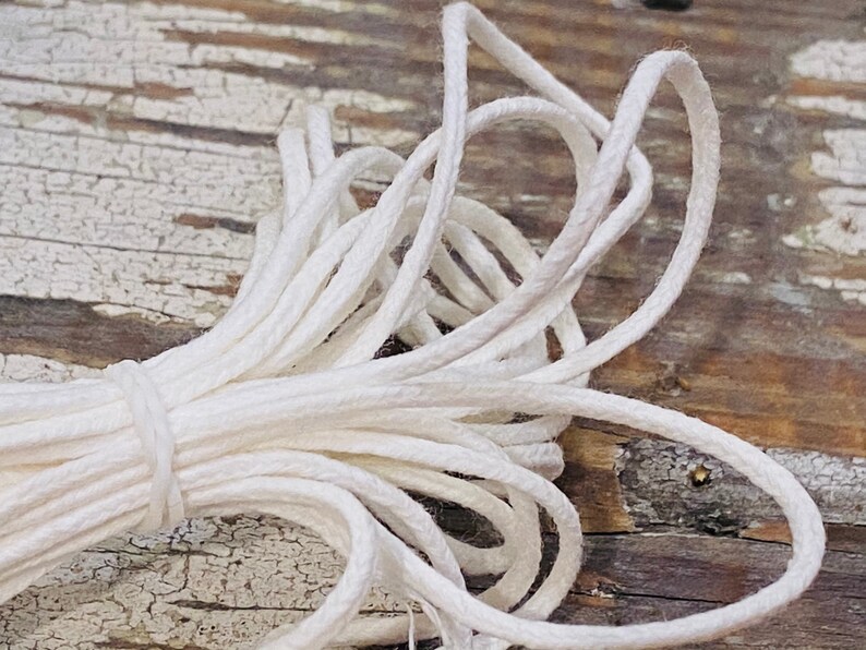May include: A close-up of a white cotton cord, twisted and bundled together. The cord is soft and pliable, perfect for crafting or jewelry making.