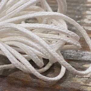 May include: White cotton cord, twisted and piled together, showing the texture of the cord.