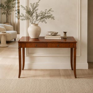 May include: A rectangular wooden console table with two drawers featuring circular metal pulls. The table has four tapered legs and a smooth, polished finish. On top sits a large, textured cream vase with green branches, a bowl, books, and a metal object.