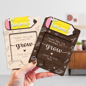 May include: Two wooden teacher appreciation plaques with a pencil design and the text "Mrs. Benjema". The plaques have a brown and a natural wood finish. The text "Thank you for helping me grow" is on both plaques. The plaques also have the text "From Oliver 2024".