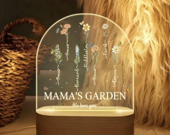 May include: A clear acrylic night light shaped like a dome with a wooden base. The dome features a floral design with butterflies and the text "Mama's Garden" and "We love you".