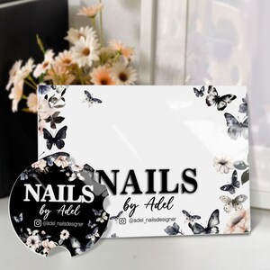Puede incluir: Una tarjeta de visita blanca y un posavasos para coche con un dise&ntilde;o floral y de mariposas. La tarjeta y el posavasos tienen el texto "NAILS by Adel" en negro, con el nombre de usuario de Instagram "@adel_nailsdesigner". El dise&ntilde;o incluye mariposas y flores negras y grises.