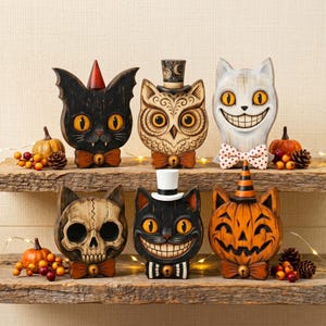 May include: Six decorative figurines featuring stylized cat and owl heads with various hats and bow ties. The collection includes a black cat with a red cone, an owl with a top hat, a white cat with a polka dot bow tie, a skull-faced cat, a black cat with a white top hat, and a pumpkin-faced cat with a striped hat.