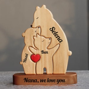 May include: Wooden bear family figurine with the names Selena, Hazel, and Ben engraved on it. The bears are hugging each other and have a red heart in the middle. The base of the figurine has the text "Nana, we love you" engraved on it.