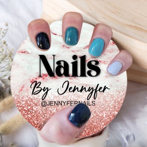 May include: A close-up of a hand with five painted nails. The nails are painted in shades of blue, black, and white. The hand is holding a round, marble-patterned surface with the text "Nails By Jennyfer @JENNYFERNAILS".