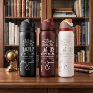 May include: Three insulated water bottles in black, burgundy, and white. Each bottle has a floral design and the text "TEACHERS plant seeds THAT GROW FOREVER" with "Mrs. Smith" and an apple graphic. The bottles are on a wooden surface.