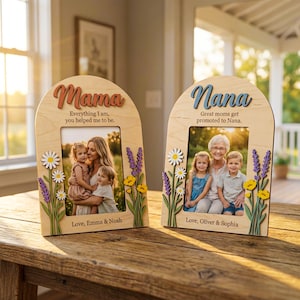 May include: Two wooden photo frames with arched tops. One says "Mama" and the other "Nana". Each frame has a photo of a family and floral embellishments. The "Mama" frame has the text "Everything I am, you helped me to be." and the "Nana" frame says "Great moms get promoted to Nana."