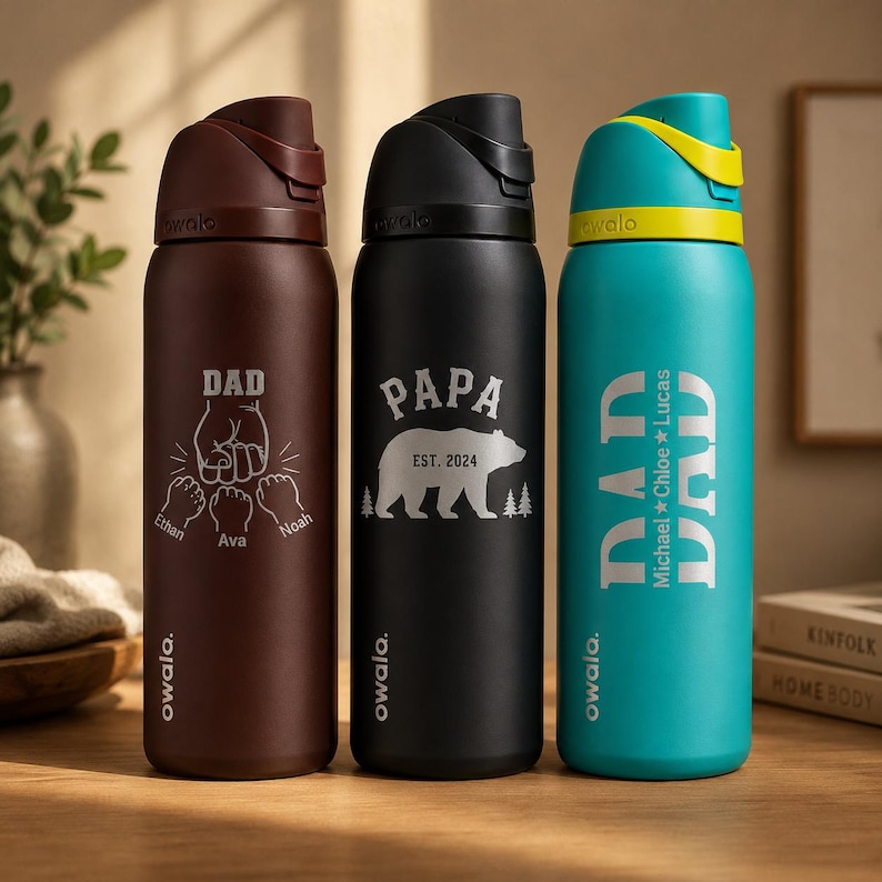 May include: Three insulated water bottles with flip-top lids. One is brown with "DAD" and fist graphic, another is black with "PAPA" and bear graphic, and the third is teal with "DAD" and names. All have the "owala" brand.