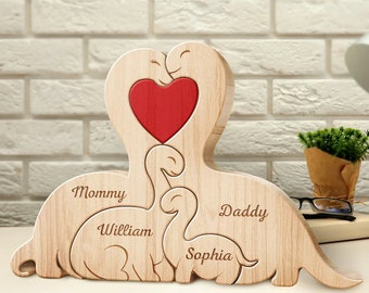Puede incluir: Corte de madera de una familia de dinosaurios con un corazón rojo en el centro. Los dinosaurios están etiquetados como "Mamá", "Papá", "William" y "Sophia".