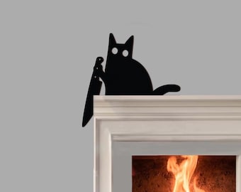 May include: A black cat silhouette holding a knife, perched on a white mantel. The cat has large, round eyes and a curved tail. The background features a fireplace with flames.