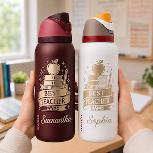 May include: Two insulated water bottles, one burgundy and one white, are held up. Each bottle has a design with an apple, books, and the text "BEST TEACHER EVER" with a name below. The burgundy bottle says "Samantha", and the white bottle says "Sophia".