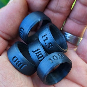 May include: Four black silicone rings with different sizes engraved on them. The sizes are 11.5, 10.5, 11, and 11.5.