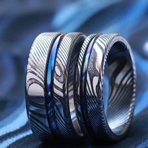 Könnte beinhalten: Zwei silberne Ringe mit einem blauen und weißen Muster. Die Ringe sind übereinander gestapelt.