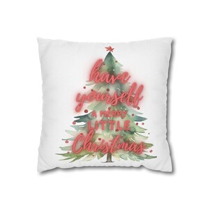 Może przedstawiać: Kwadratowa biała poduszka dekoracyjna z akwarelową ilustracją zielonej choinki. Napis "have yourself A MERRY LITTLE Christmas" jest nadrukowany na czerwono na drzewku, które jest zwieńczone małą czerwoną gwiazdką i czerwonymi ozdobami.