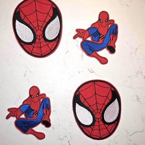 May include: Four embroidered patches featuring the character Spider-Man. Two patches are circular with a red and black web pattern and large white eyes. Two patches depict the character in a crouching pose with red and blue fabric details.
