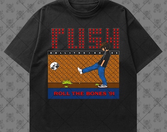 May include: A black short-sleeve t-shirt featuring a graphic print with the text RUSH in red dots, the words ROLL THE BONES, and a figure kicking a skull. The design includes a brown grid background, blue jeans, and the text ROLL THE BONES '91.