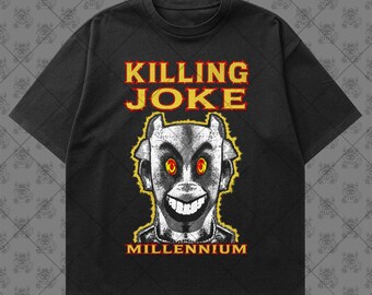 May include: A black short-sleeve t-shirt featuring a graphic print with the text KILLING JOKE at the top and MILLENNIUM at the bottom. The central image is a stylized, monochromatic creature face with wide, glowing yellow and red eyes and a grin.
