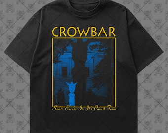 May include: A black short-sleeve t-shirt featuring a yellow rectangular frame with the text CROWBAR at the top and Sonic Excess In It's Purest Form at the bottom. Inside the frame is a blue graphic of a statue and trees against a building.
