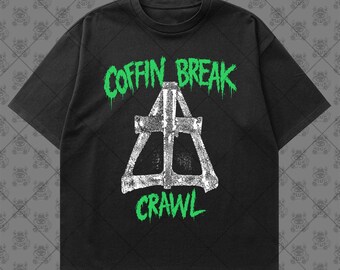 May include: A black short-sleeve t-shirt featuring a graphic print with the text COFFIN BREAK in bright green, a central white distressed triangular structure, and the word CRAWL in bright green lettering positioned below the graphic.