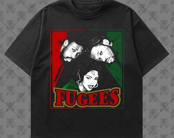 May include: A black short-sleeve t-shirt featuring a graphic print of the musical group Fugees. The design includes portraits of three individuals set against red and green panels, with the word FUGEES printed in large red letters below.