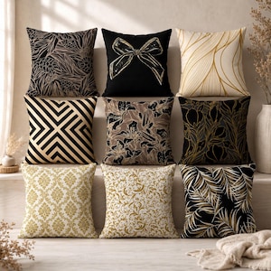 Könnte beinhalten: Eine Sammlung von neun quadratischen Dekokissen mit verschiedenen Mustern in Schwarz, Gold und Creme. Die Designs umfassen botanische Blätter, eine zentrale Schleife, geometrische Linien, florale Motive, Damastdrucke und Rankenmuster.