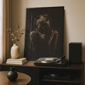 Peut inclure: Une impression d'art mural verticale encadrée présentant un croquis abstrait et sombre d'une silhouette en lignes beige clair sur fond noir. L'œuvre est exposée sur une console en bois foncé à côté d'un vase beige côtelé et d'un tourne-disque noir.