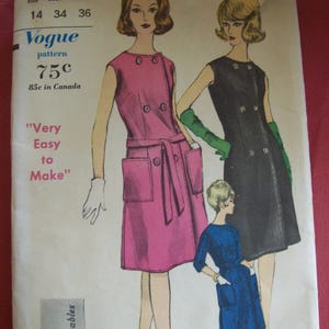 May include: Vintage Vogue pattern 5597 featuring illustrations of three dresses. The dresses are in pink, black, and blue, with double-breasted button details and pockets. The pattern includes the text "Very Easy to Make."