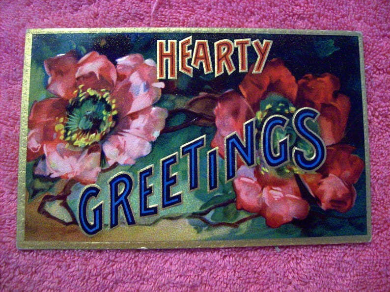 Puede incluir: Postal vintage con ilustraciones florales y las palabras "Hearty Greetings". Las flores son en tonos de rojo, rosa y verde, con un borde dorado. El texto est&aacute; en una fuente estilizada con acentos azules y dorados.