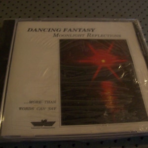 May include: A sealed music CD case titled Dancing Fantasy Moonlight Reflections. The cover features a white background with black text and a rectangular image of a red star-like light reflecting over dark water. The text reads More Than Words Can Say.