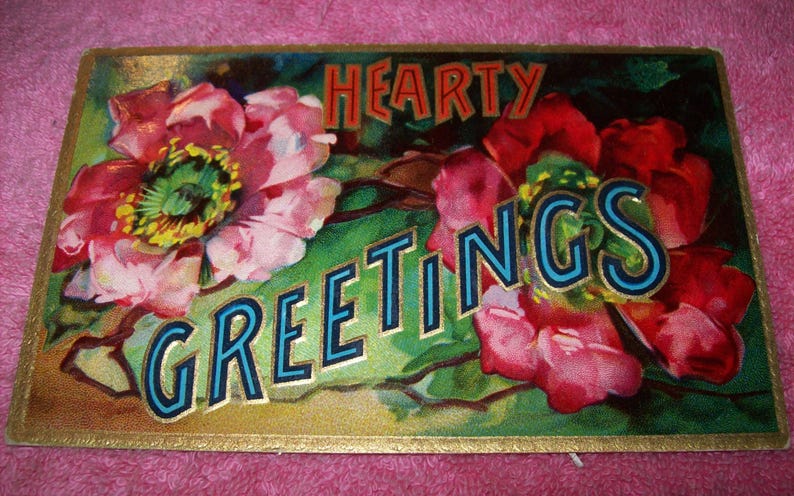 Puede incluir: Postal vintage con dise&ntilde;o floral. La tarjeta presenta las palabras "Hearty Greetings" en letras en negrita. Las flores son en tonos de rosa, rojo y verde, con un borde dorado. El fondo es una mezcla de verde y dorado.
