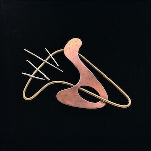 May include: A brooch featuring a curved copper plate with a central oval cutout, intertwined with a thin gold-toned wire frame. Three short, parallel silver-toned metal rods are attached to the upper left side of the wire structure.