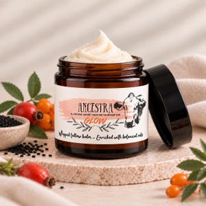 Op de afbeelding: Een amberkleurige glazen pot gevuld met witte opgeklopte talkbalsem, afgesloten met een zwarte deksel. Het etiket bevat de tekst ANCESTRA GLOW, ALL NATURAL ANCIENT TRADITION FOR MODERN SKIN en Whipped tallow balm - Enriched with botanical oils.