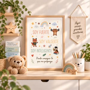 Puede incluir: Una lámina enmarcada con el texto en español Soy Fuerte, Soy Valiente, Soy Inteligente y Puedo conseguir lo que me proponga, decorada con ilustraciones de un oso levantando pesas, un zorro superhéroe y un búho con libros.
