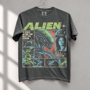 Peut inclure: Un t-shirt gris anthracite à manches courtes avec une impression graphique du film Alien. Le design inclut le texte ALIEN, IN SPACE NO ONE CAN HEAR YOU SCREAM, IT'S A PERFECT ORGANISM, et FROM DIRECTOR RIDLEY SCOTT, avec des scènes de la créature.