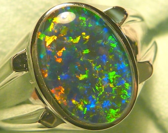 May include: A silver ring with a large oval-shaped black opal gemstone. The opal has a green, blue, and orange iridescent sheen.