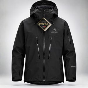 Può includere: Una giacca con cappuccio nera Arc'teryx dotata di cerniera frontale integrale, due ampie tasche verticali sul petto e una tasca sulla manica. Un'etichetta Gore-Tex pende dalla cerniera e il logo del marchio è stampato sul petto.
