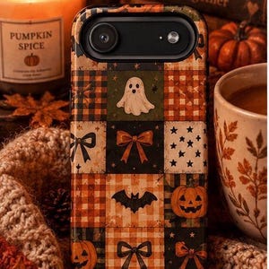 May include: A rectangular phone case featuring a patchwork grid design with various Halloween-themed illustrations including a white ghost, orange pumpkins, black bats, and bows in shades of orange, black, and cream against plaid and star patterns.
