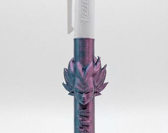 May include: A multi-color ballpoint pen featuring a white top section with the BIC logo and a custom 3D-printed lower barrel. The lower barrel has a metallic purple and blue finish, a sculpted head of the character Vegeta, and the name VEGETA embossed.